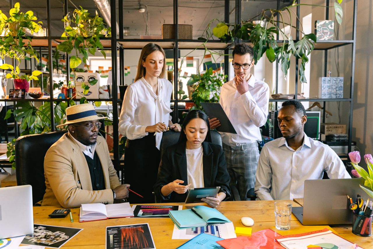 A diverse team of professionals collaborating on a project in a lively office setting.