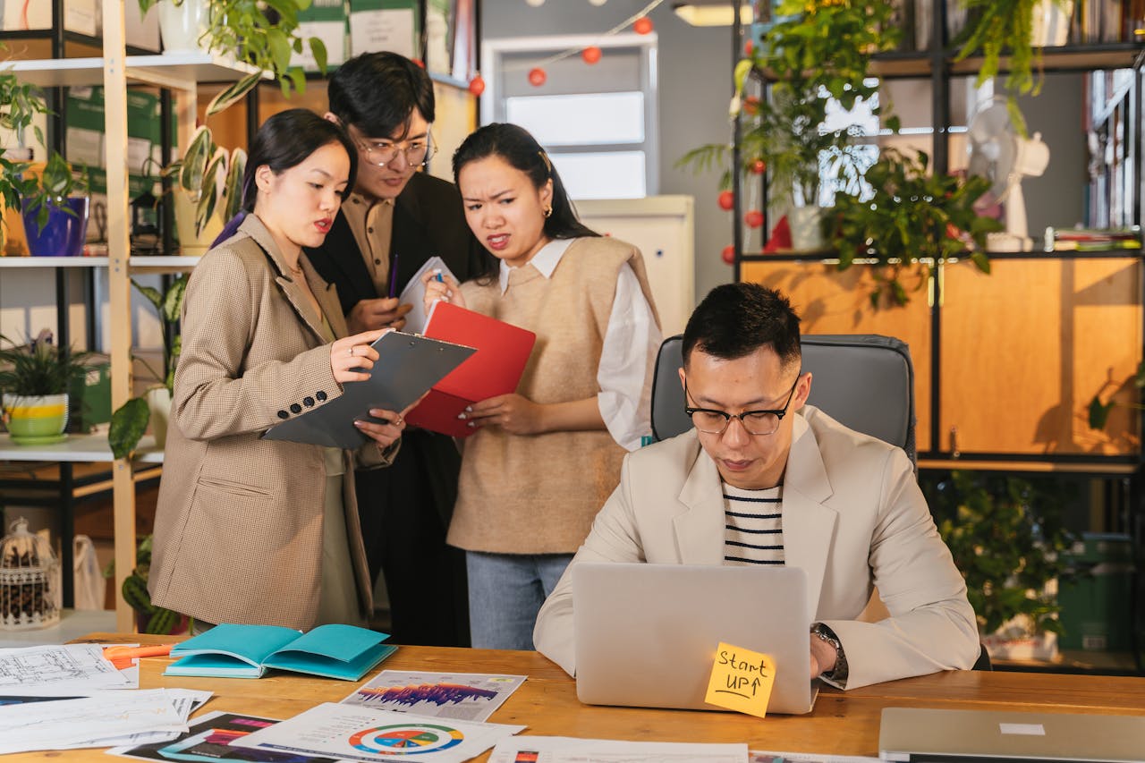Group of colleagues engaged in a team meeting in a vibrant, plant-filled office.